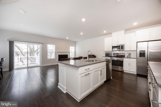 kitchen featuring stainless steel appliances, sink, a kitchen island with sink, and white cabinets