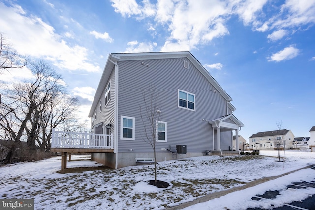 snow covered house with a deck and central air condition unit