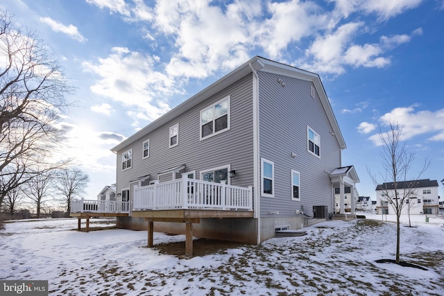 snow covered back of property featuring a wooden deck and central AC unit