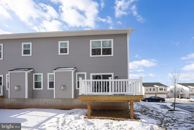 snow covered rear of property with a wooden deck