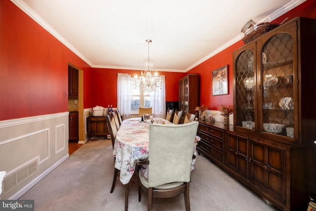 carpeted dining room with crown molding and a chandelier