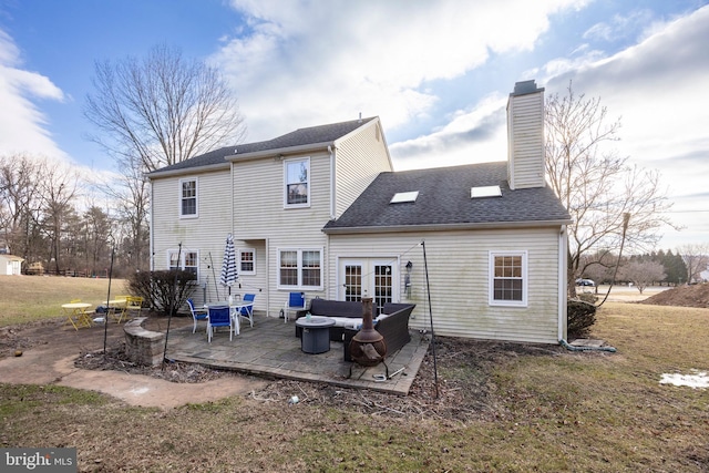 rear view of property featuring french doors, a lawn, an outdoor living space, and a patio area