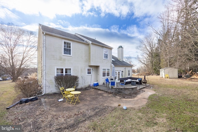 back of property with an outdoor living space, a yard, a shed, and a patio area