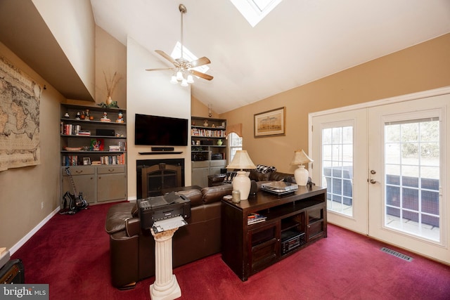 carpeted living room with lofted ceiling with skylight, ceiling fan, and french doors