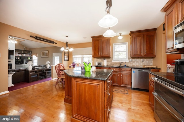 kitchen featuring stainless steel appliances, hanging light fixtures, a center island, and light hardwood / wood-style floors