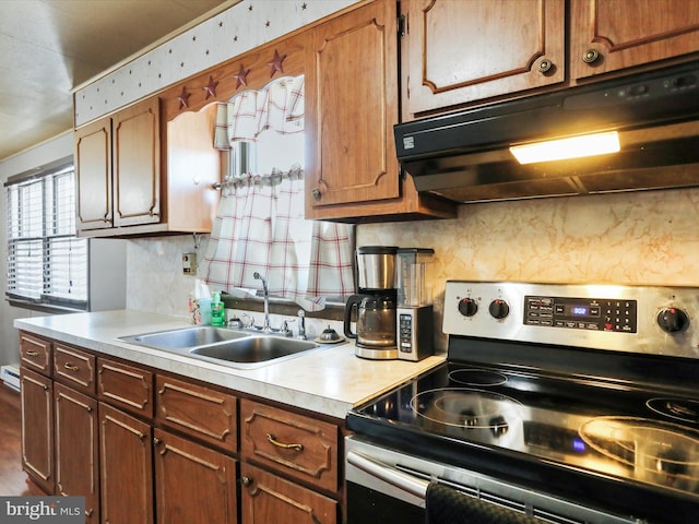 kitchen featuring tasteful backsplash, sink, baseboard heating, and stainless steel range with electric stovetop