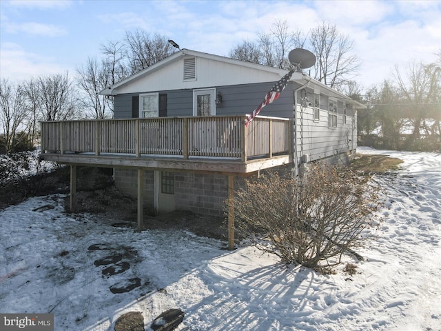 snow covered back of property featuring a deck