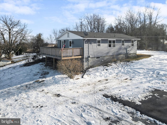 snow covered house featuring a wooden deck