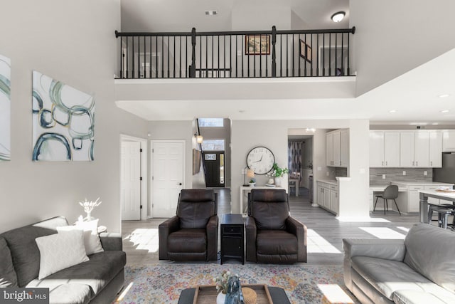 living room featuring a towering ceiling and light wood-type flooring