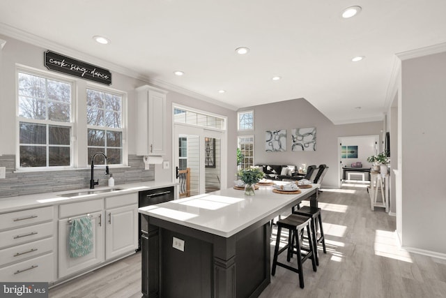 kitchen with ornamental molding, a center island, sink, and white cabinets