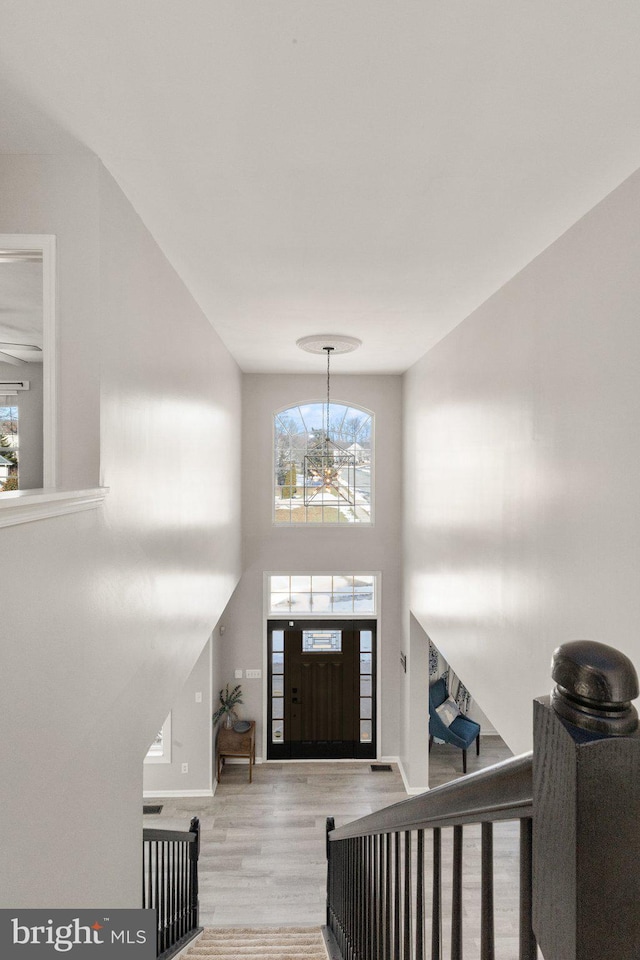 foyer with a high ceiling, a notable chandelier, and light hardwood / wood-style flooring