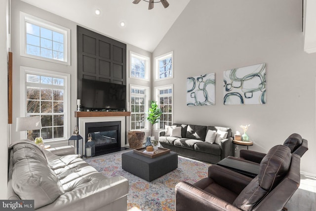 living room with ceiling fan, light wood-type flooring, and high vaulted ceiling