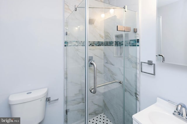 bathroom featuring toilet, a shower with door, and vanity