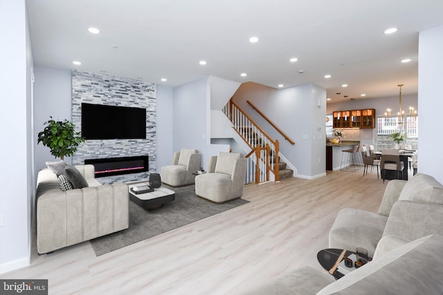 living room with light wood-type flooring, a notable chandelier, and a tiled fireplace