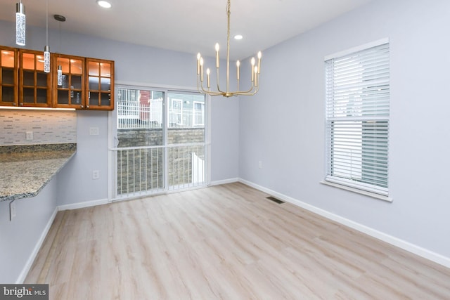 unfurnished dining area featuring light wood-type flooring and a notable chandelier