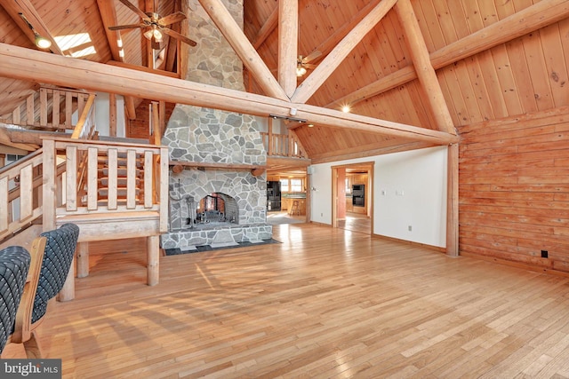 unfurnished living room featuring wood walls, beamed ceiling, hardwood / wood-style flooring, wood ceiling, and high vaulted ceiling