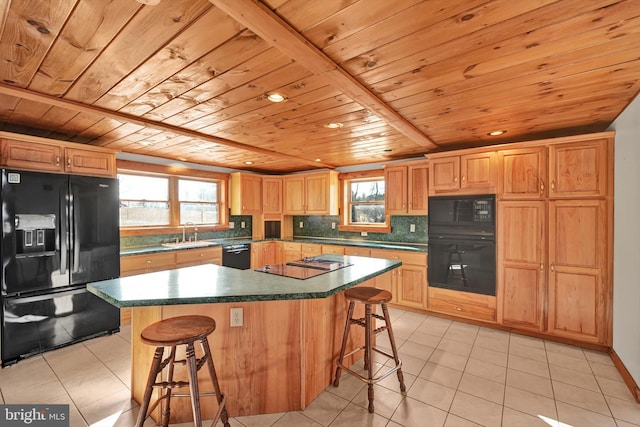 kitchen featuring a breakfast bar, black appliances, sink, and a kitchen island