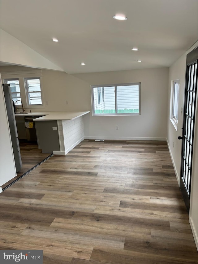 kitchen featuring hardwood / wood-style flooring, sink, kitchen peninsula, and stainless steel refrigerator