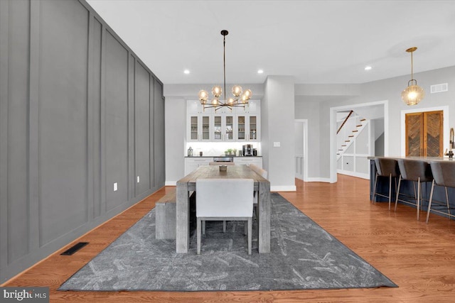 dining space featuring visible vents, recessed lighting, stairs, and wood finished floors