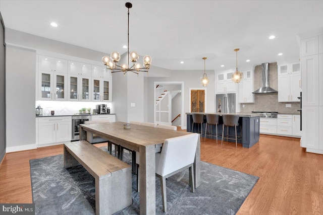 dining area featuring recessed lighting, light wood-type flooring, wine cooler, and stairway