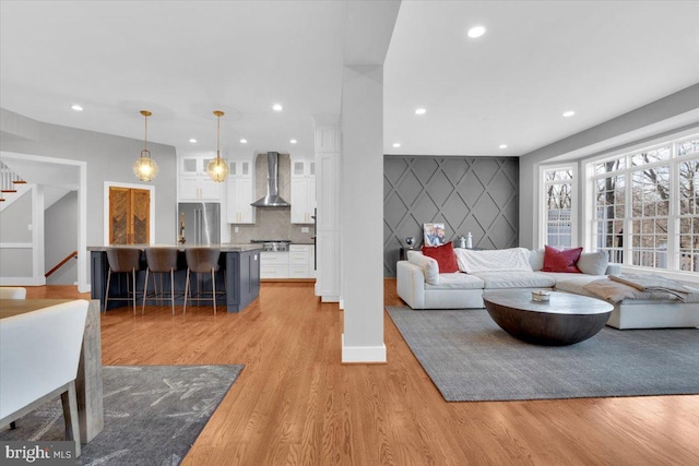 living area featuring an accent wall, stairs, light wood-style floors, and recessed lighting