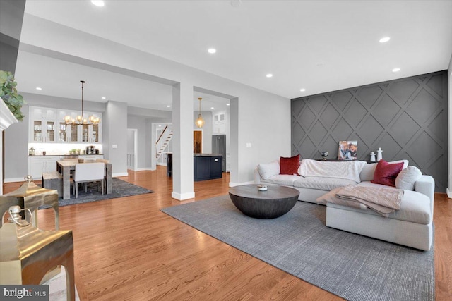 living room with an accent wall, recessed lighting, light wood-type flooring, and baseboards