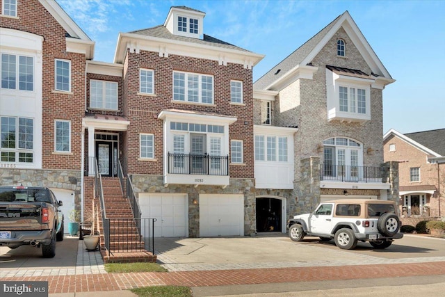 multi unit property featuring brick siding, stone siding, driveway, and an attached garage