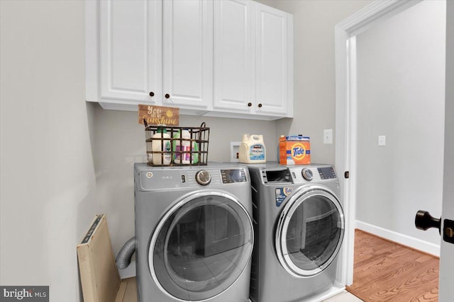 washroom featuring cabinet space, washer and dryer, baseboards, and wood finished floors