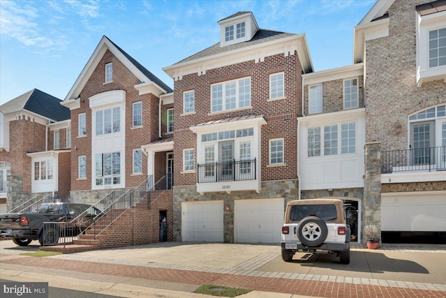 view of front of house with a garage, brick siding, stone siding, and driveway