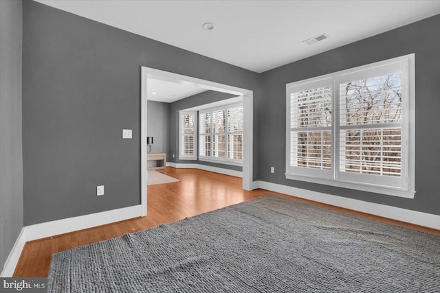 spare room with visible vents, baseboards, and wood finished floors