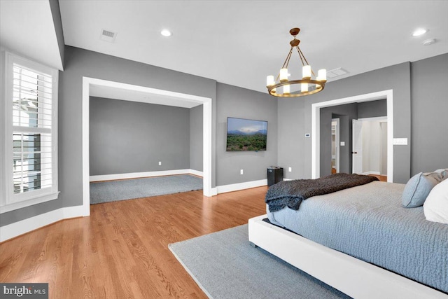 bedroom featuring visible vents, baseboards, light wood-type flooring, recessed lighting, and an inviting chandelier