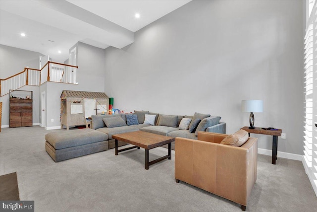 living area with baseboards, recessed lighting, stairs, a towering ceiling, and light colored carpet