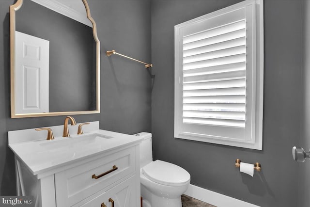 half bath featuring toilet, vanity, and baseboards