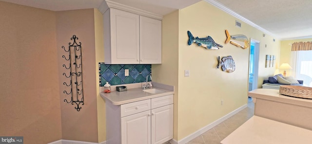 kitchen featuring tasteful backsplash, sink, crown molding, and white cabinetry