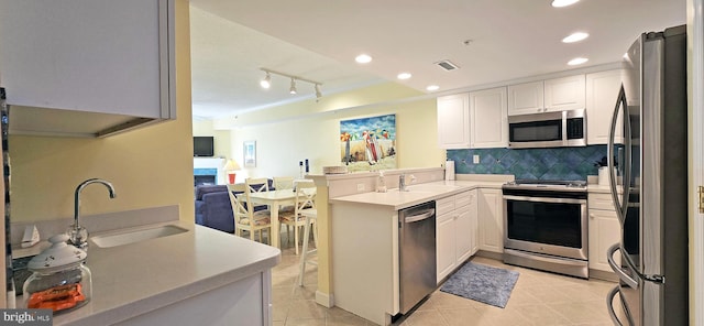 kitchen featuring track lighting, white cabinetry, stainless steel appliances, sink, and kitchen peninsula