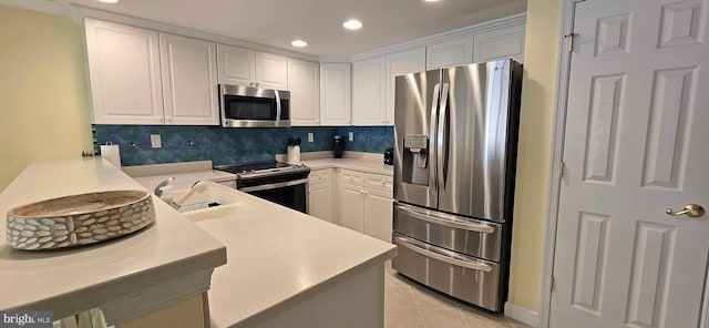 kitchen with kitchen peninsula, stainless steel appliances, white cabinets, and sink