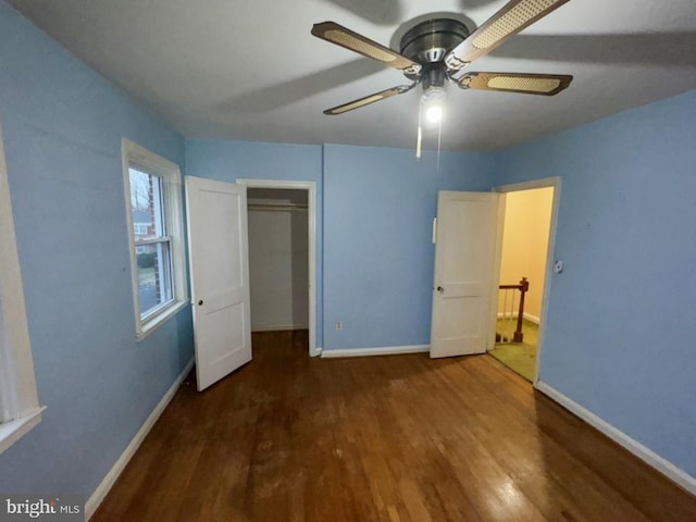 unfurnished bedroom with dark wood-type flooring, ceiling fan, and a closet