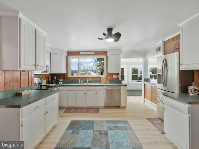 kitchen featuring white cabinets, appliances with stainless steel finishes, sink, and light wood-type flooring