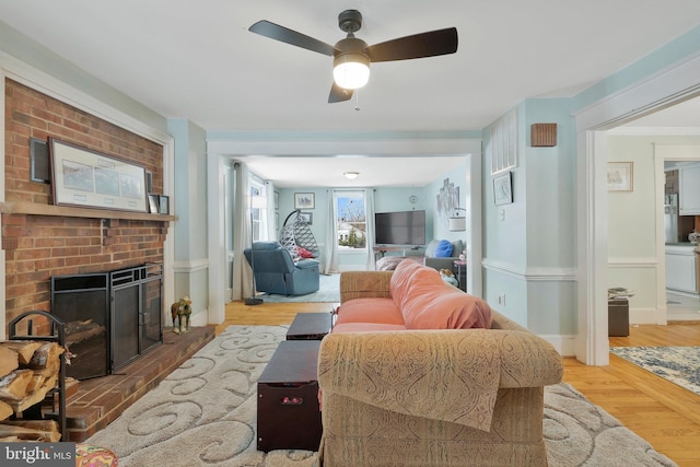 living room featuring ceiling fan, wood-type flooring, and a fireplace