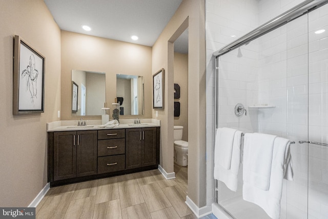 bathroom featuring toilet, an enclosed shower, and vanity