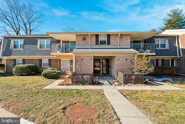 townhome / multi-family property with a balcony, a front yard, and central air condition unit