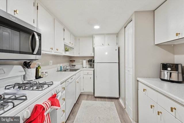 kitchen featuring white cabinets, light wood-type flooring, sink, and white appliances