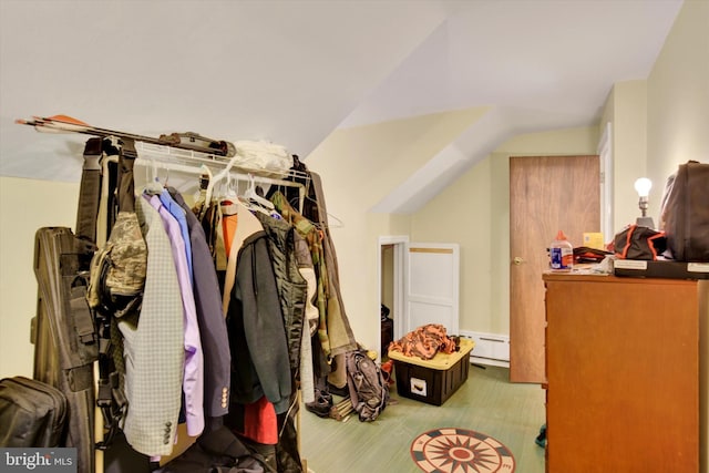 walk in closet featuring a baseboard radiator and lofted ceiling