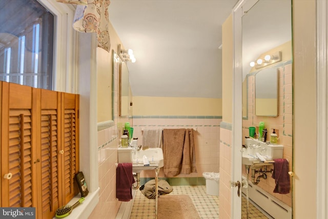 bathroom with lofted ceiling, tile walls, and a baseboard radiator