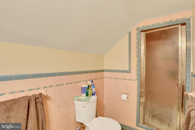 bathroom with lofted ceiling, toilet, tile walls, and an enclosed shower