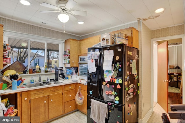 kitchen with ceiling fan, sink, black fridge, and stainless steel oven