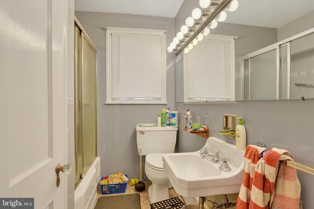 full bathroom featuring toilet, bath / shower combo with glass door, and sink