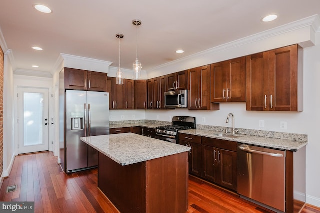 kitchen with sink, decorative light fixtures, a center island, ornamental molding, and stainless steel appliances