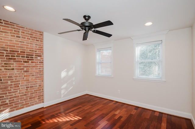 spare room featuring wood-type flooring and brick wall