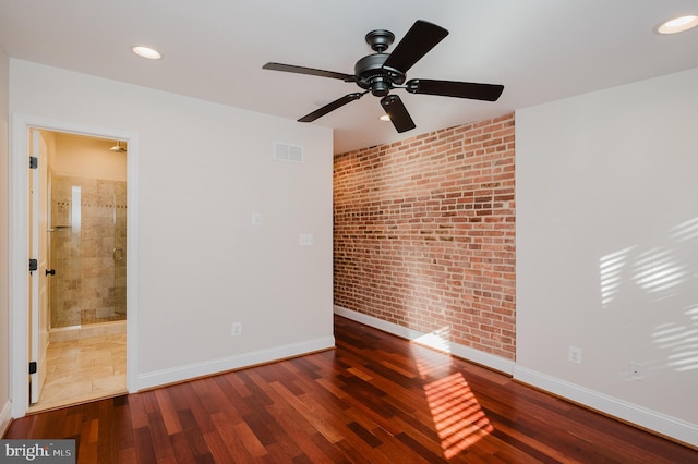 empty room with brick wall, dark wood-type flooring, and ceiling fan